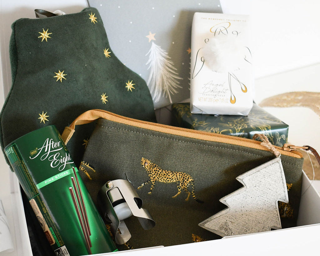 Green pouch with gold animal design, green box, and white item in a box on a white background